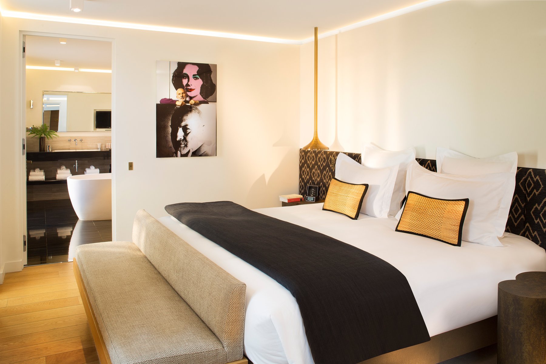 Chambre élégante de l’Hôtel Marignan avec coin salon et salle de bain ouverte