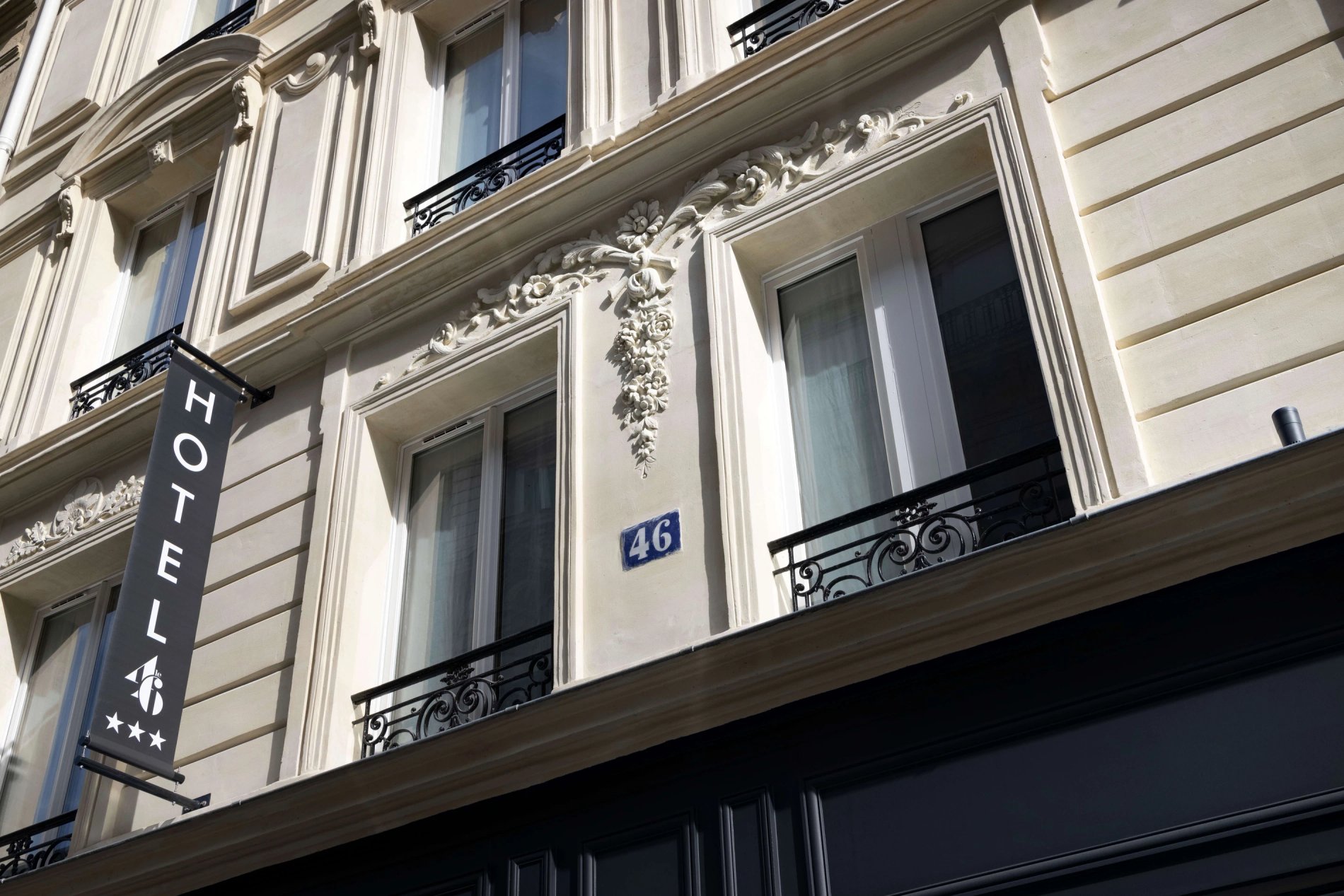 Hotel Le 46 sign on a typical Parisian building front