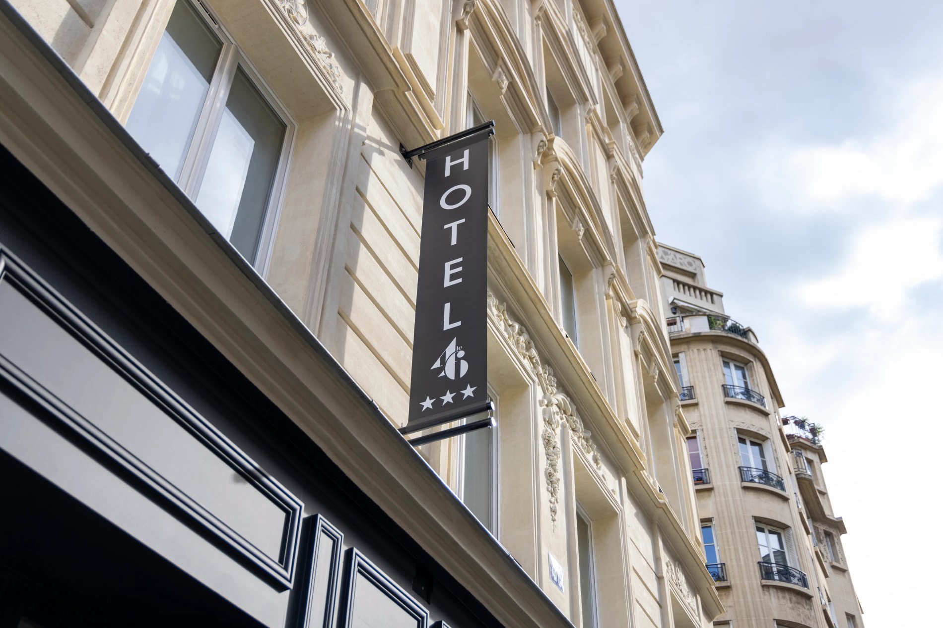 Enseigne verticale de l’hôtel Le 46 sur façade haussmannienne à Paris