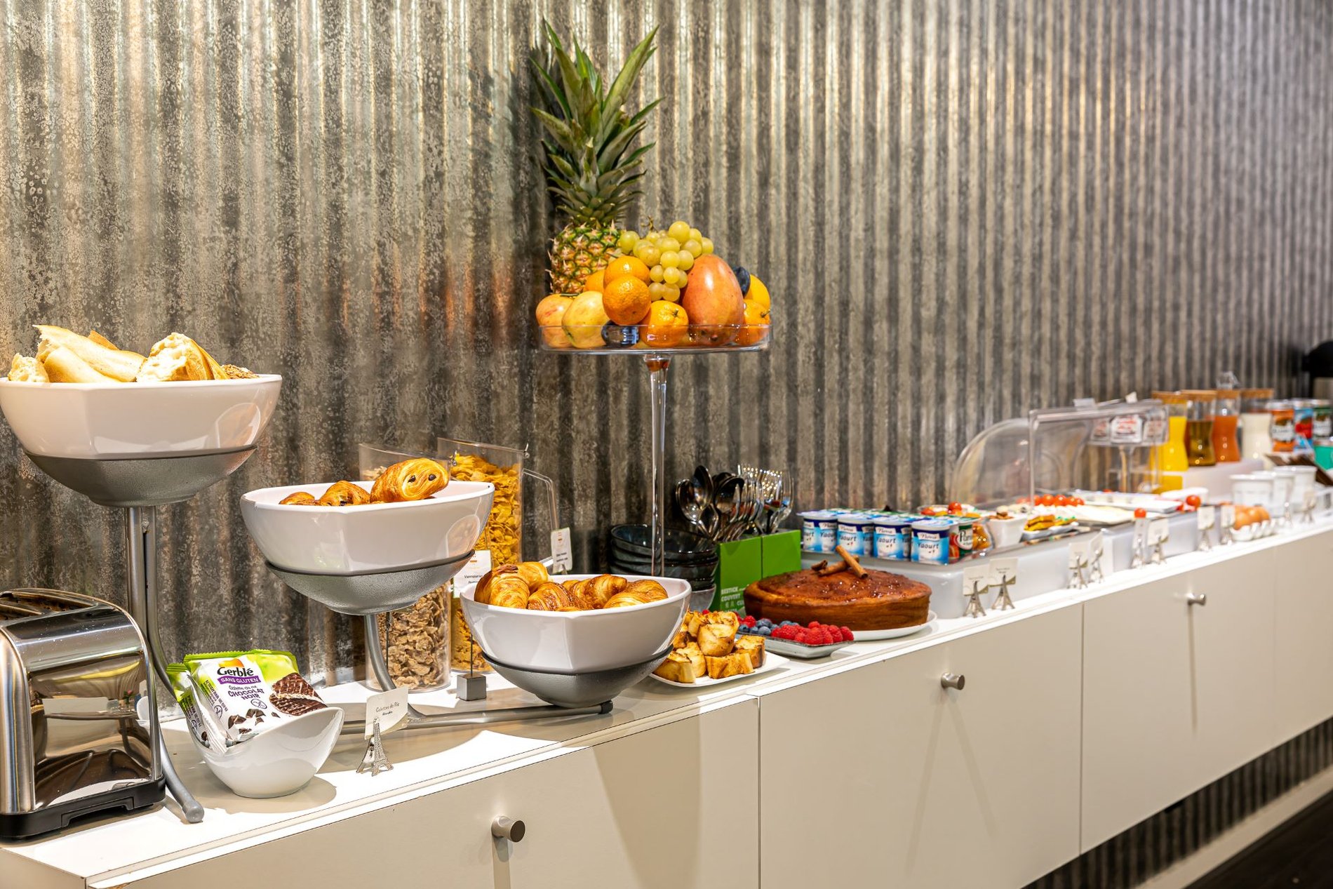 Buffet de petit-déjeuner à l'Hôtel Glasgow Monceau avec fruits frais, gâteau fait maison, croissants et pain perdu.