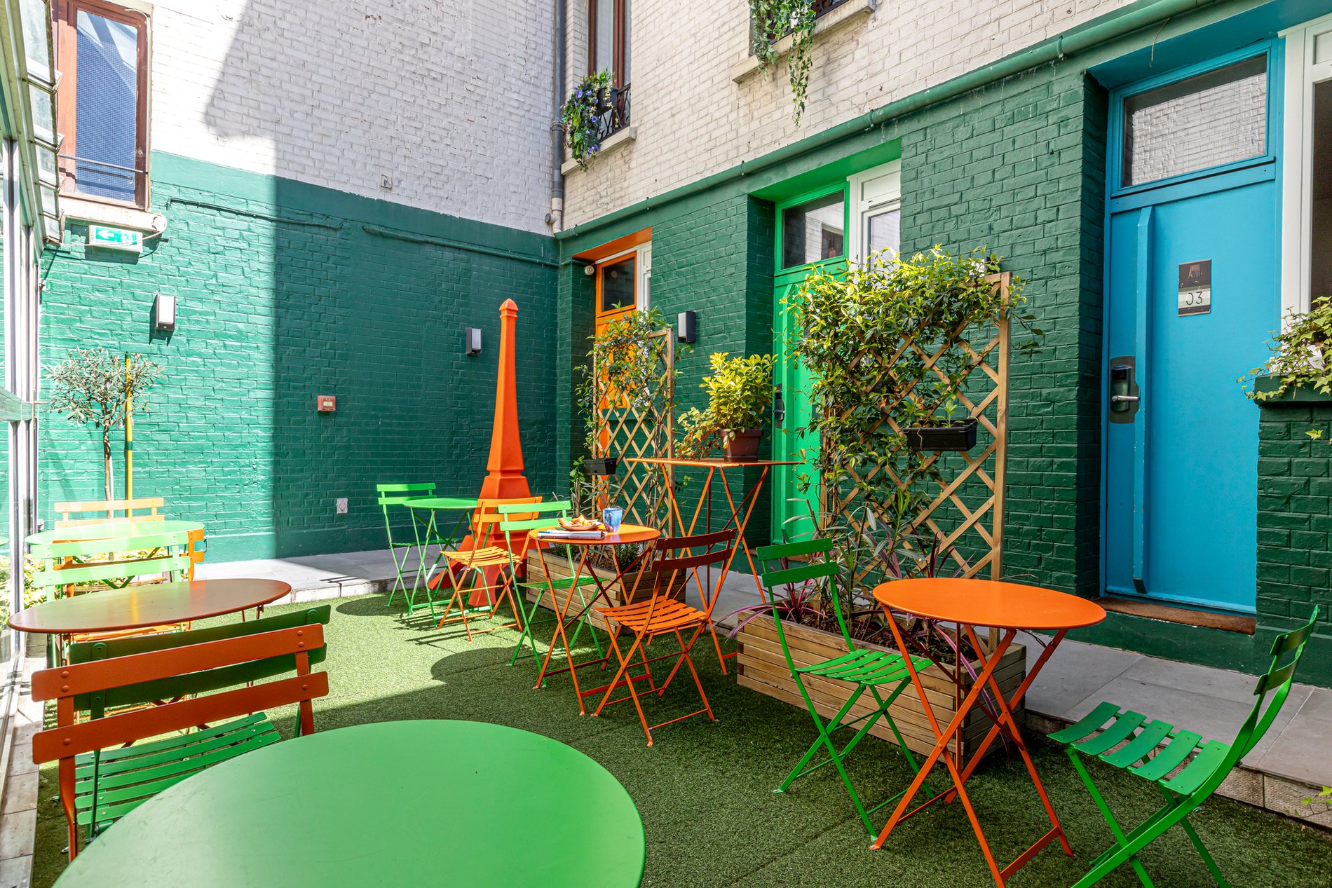 Patio de l'hôtel Alpha Paris Eiffel à Boulogne-Billancourt, avec tables et chaises de jardin pour se détendre.