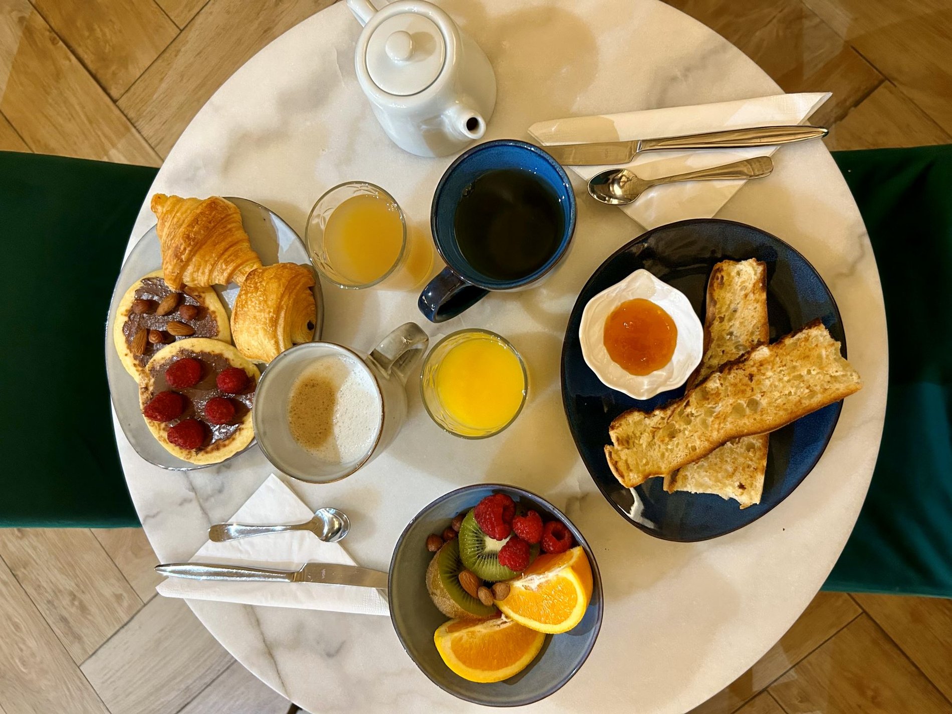 Petit-déjeuner gourmet à l'Hôtel du Théâtre, Paris 17e, avec des viennoiseries fraîches, des fruits, du café et du jus d'orange. Parfait pour bien commencer la journée avant de visiter le Parc Monceau, l'Arc de Triomphe et les Champs-Elysées.