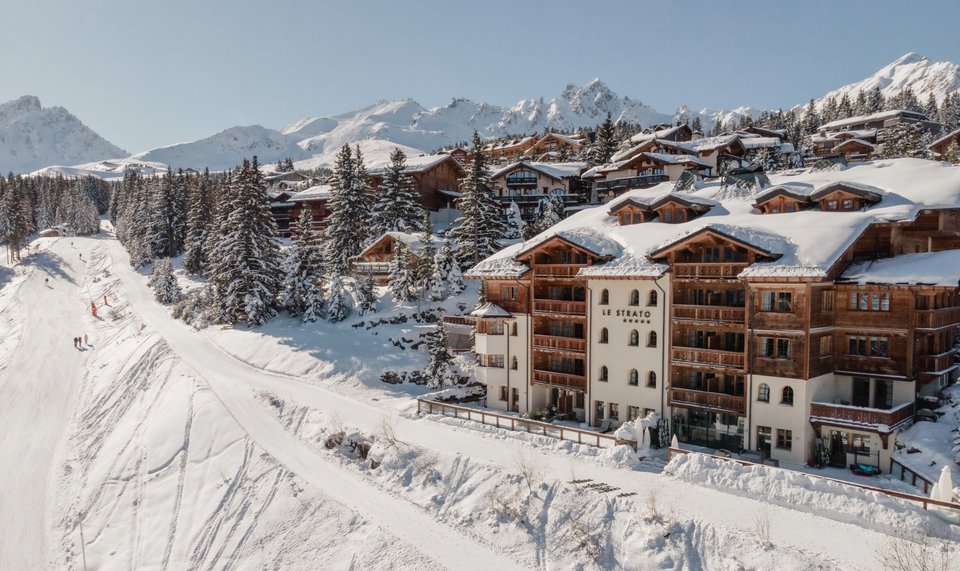 Façade enneigée de l’hôtel Le Strato à Courchevel 1850 avec vue sur les montagnes alpines