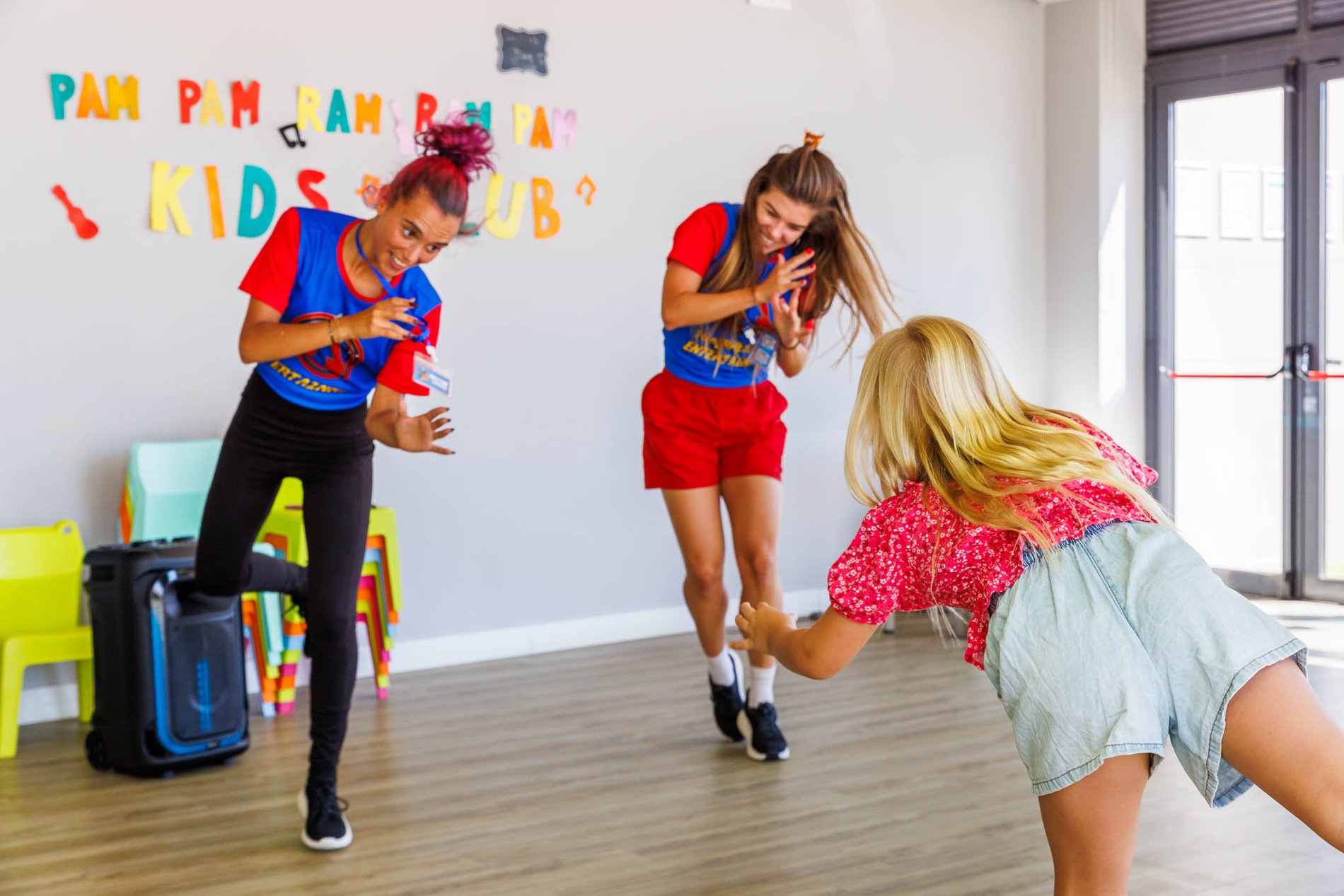 Kind tanzt mit zwei Betreuerinnen im Kids Club des Jupiter Albufeira Hotels