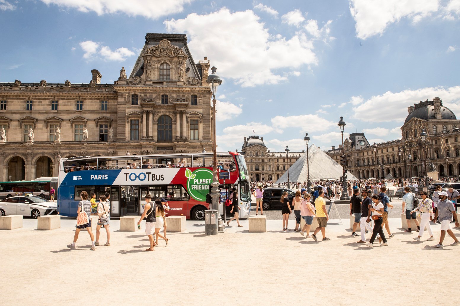 Bus panoramique Tootbus passant devant la Tour Eiffel à Paris
