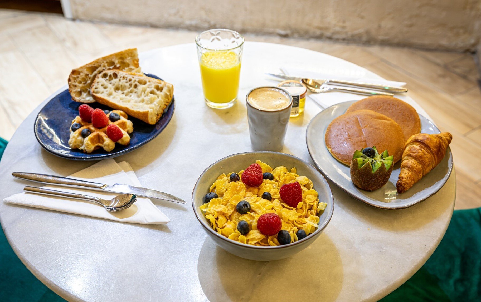 Petit déjeuner copieux à l'Hôtel Romance Malesherbes, Paris, servi dans une salle voûtée.