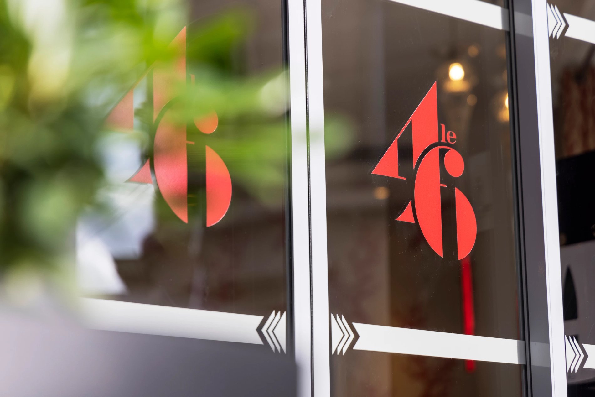 Logo rouge de l’hôtel Le 46 sur porte vitrée