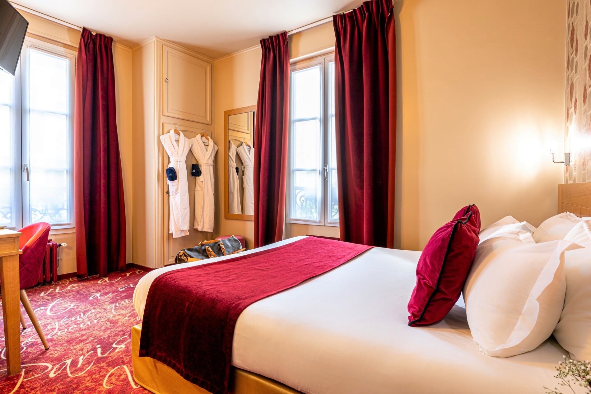 Chambre Musset à l'Hôtel Romance Malesherbes, Paris 17ème, décorée en rouge avec des peignoirs et un sac de voyage. Proche de Montmartre, Parc Monceau, et Champs-Elysées.