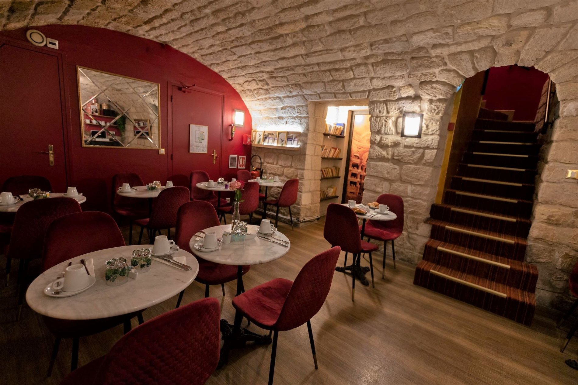 Salle de petit-déjeuner voûtée de l'Hôtel du Théâtre à Paris, offrant une atmosphère chaleureuse et conviviale.